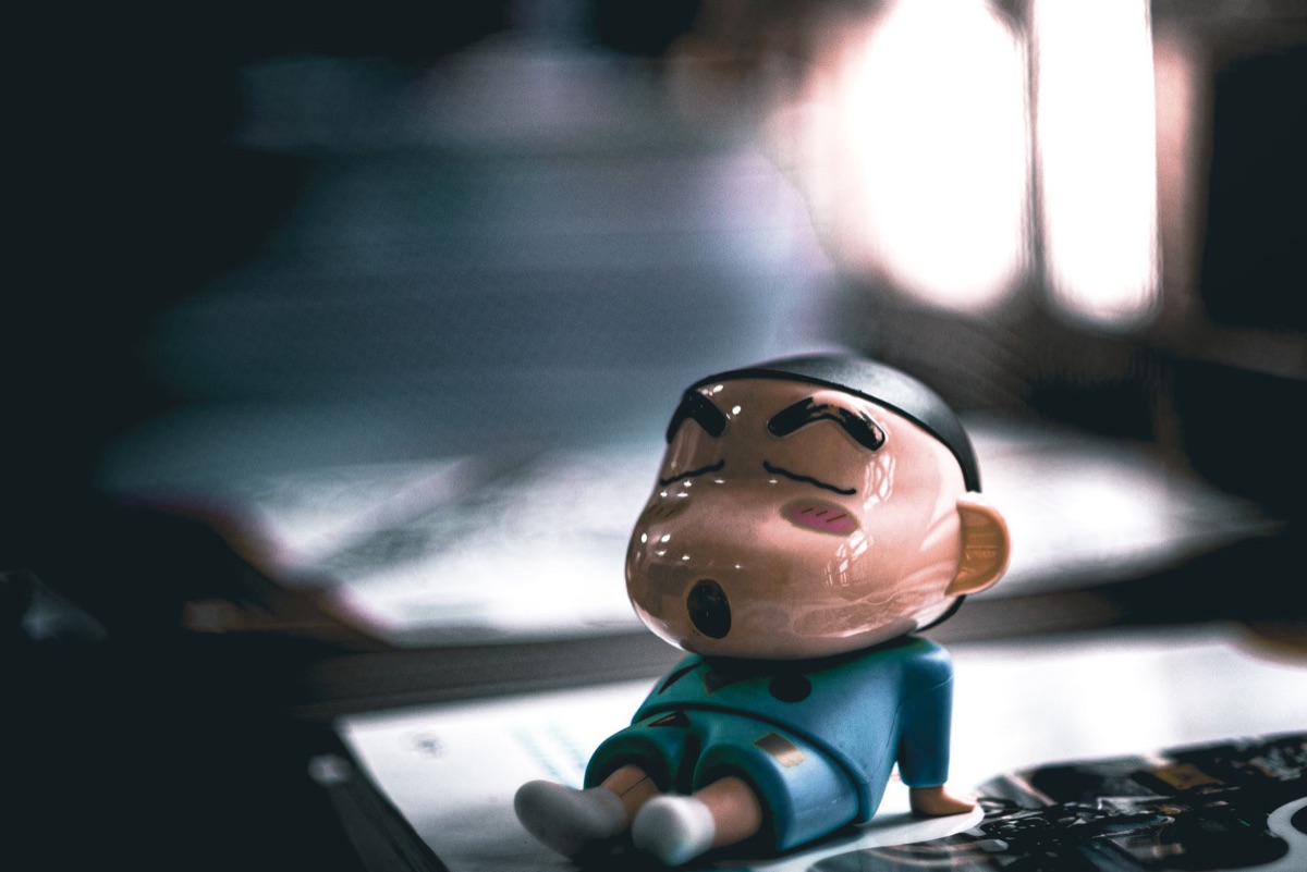 A detailed anime character figurine placed next to a smartphone on a wooden desk.