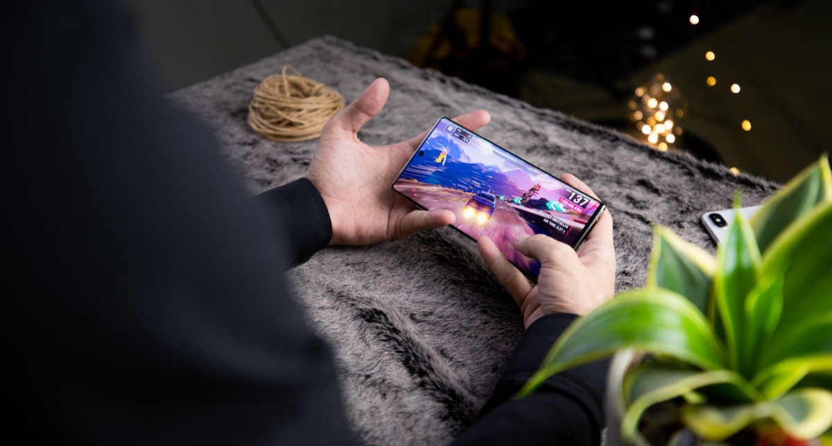 Una mano che tiene uno smartphone con un gioco d'animazione sullo schermo.