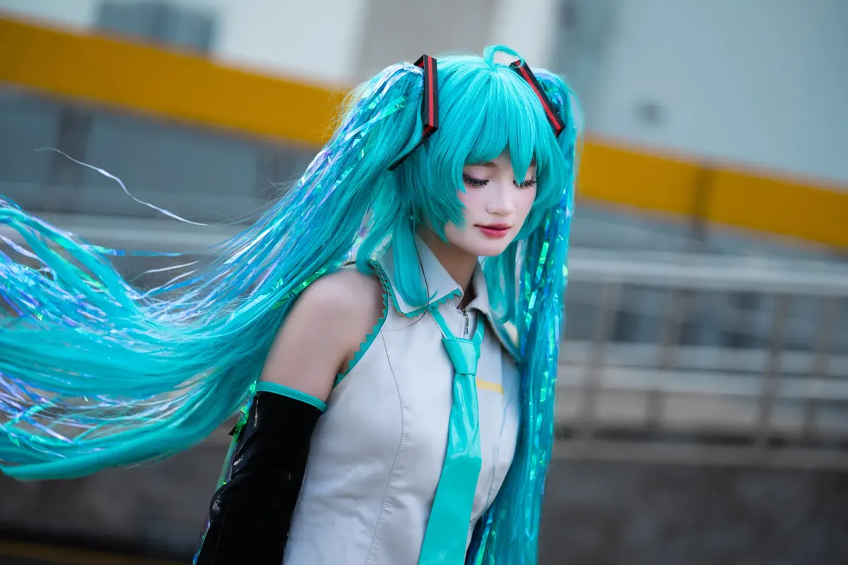 A young adult in a vibrant anime-inspired cosplay with turquoise hair, posing outdoors in an urban setting.